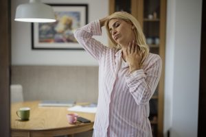 A person doing a gentle morning stretch beside a window at home in soft daylight.